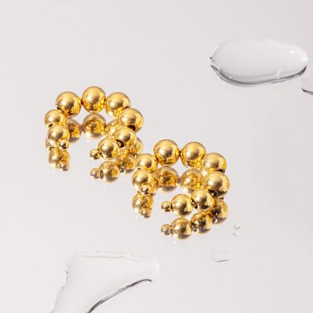 Toma artística del arete de perlas doradas.
