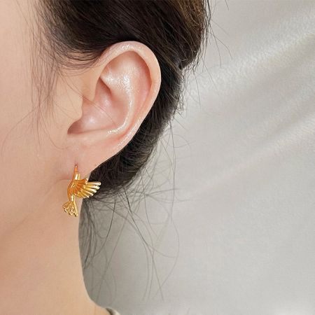 Model wearing the matte gold 3D bird stud earring to show scale and style.