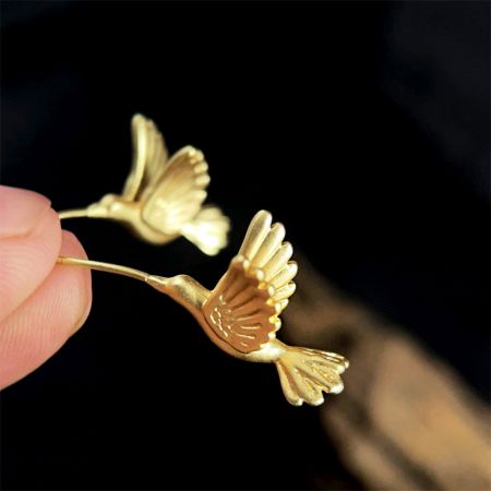 Front view of the brass matte gold bird earrings, displaying their unique three-dimensional shape.