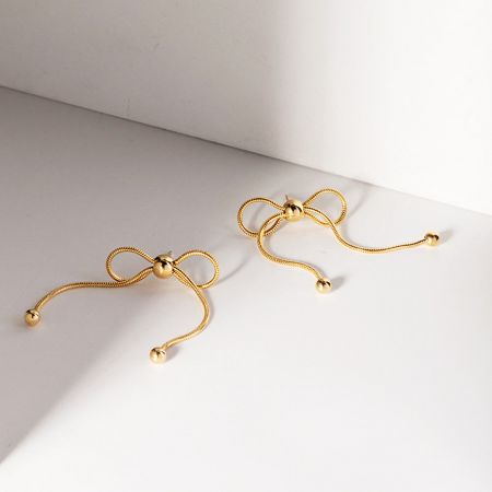 Un par de pendientes de aro con nudo dorado de acero inoxidable sobre un fondo blanco.