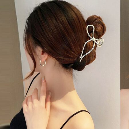 Toma detallada de un delicado clip de pelo en forma de lazo dorado.