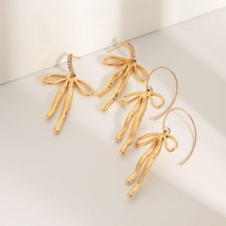 Drie paar gouden strik oorbellen met franjes, samen weergegeven.