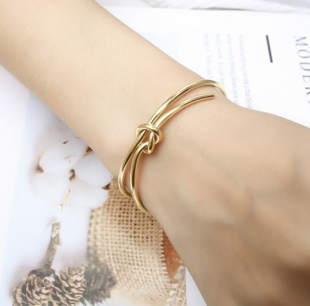 A lifestyle image showing the gold Bow Cuff Bracelet worn on a wrist, demonstrating its elegant look.