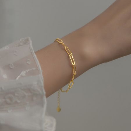 Imagem de estilo de vida da pulseira de clipe de papel de prata esterlina dourada em um pulso.