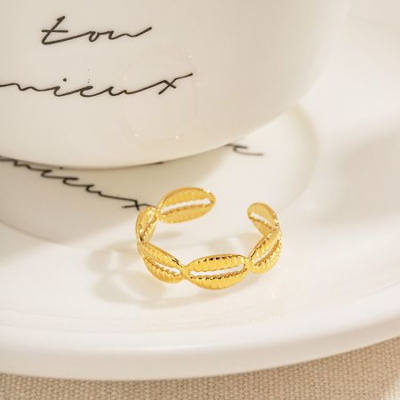 Roestvrijstalen waterdichte gouden cowrie-schelp open ringen set van 5 - Een set van vijf roestvrijstalen vergulde cowrie-schelp open ringen, elegant gepresenteerd op een wit schoteltje.