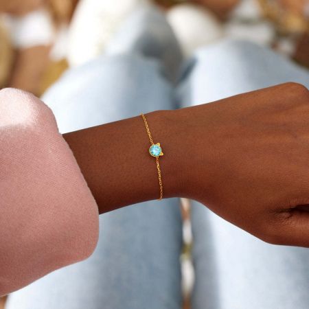 Close-up of the gold-tone cat bracelet with a blue CZ stone worn on a wrist, showcasing its elegant fit.