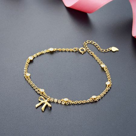 925 Sterling Zilver Vergulde Twee Laags Ketting Strikbedelarmbanden - Close-up van een 925 sterling zilveren, vergulde kettingarmband met twee lagen, met een elegante strikbedel met heldere stenen. Onderdeel van een set van 5.