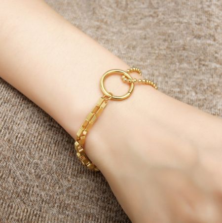 Close-up of the gold bracelet's circular clasp and mixed links.