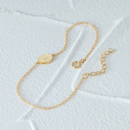 Una pulsera dorada minimalista con un solo acento de circonio brillante.