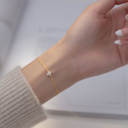 Gold version of the four-leaf clover charm bracelet worn on a wrist.