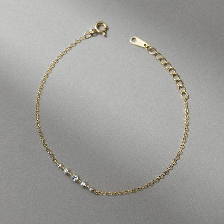 Full view of a delicate gold chain bracelet showing the lobster clasp and extender chain.