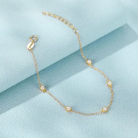 Pulsera de cadena de plata esterlina 925 de 5 circonitas al por mayor (Juego de 5) - Una delicada pulsera de cadena de plata esterlina 925 en acabado dorado, con cinco piedras de circonita brillantes, exhibida sobre un fondo azul claro.