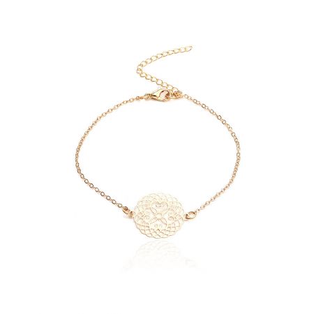Vista dettagliata del bracciale in catena d'oro con un ciondolo a disco inciso a fiori.