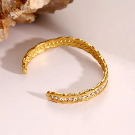 Detailed view of a single gold-plated zircon cuff bracelet showcasing its textured surface and sparkling gemstone setting.