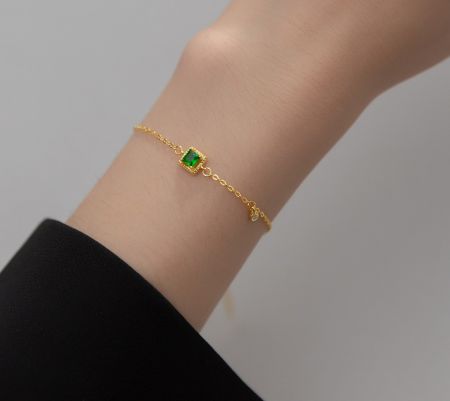 Detailed view of the emerald centerpiece on the gold plated sterling silver bracelet.