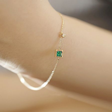 Detailed view of the gold-plated sterling silver bracelet with its vibrant green emerald zircon.