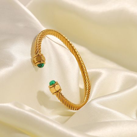 Ovanifrån vy av armbandet i rostfritt stål med livfulla gröna ädelstenar.