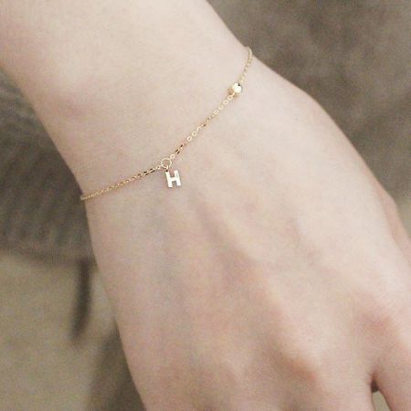 Clean product shot of the gold-finished H charm bracelet against a white background.