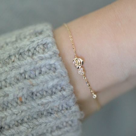 925 Zilver Vergulde Kleine Rozenbloem met Zirconia Hart Armband - Een delicate vergulde armband van 925 sterling zilver met een kleine roos en een sprankelend zirconia hart charme, gedragen om een pols.
