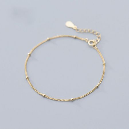 Detailed view of the gold bracelet's clasp and extension chain.