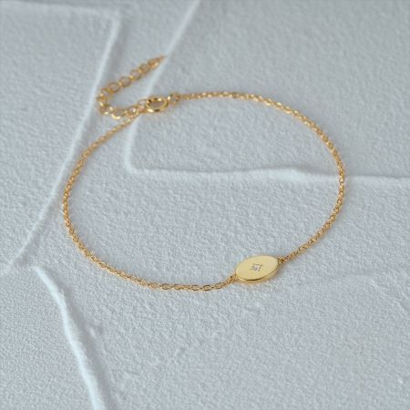 Primer plano de la pulsera de charm de estrella dorada con una piedra de circonio central en una muñeca.