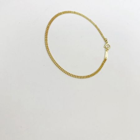 Detailed view of the textured beads and clasp on the gold bracelet.
