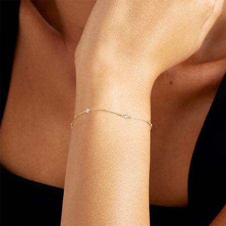 Primer plano de la pulsera de plata esterlina de 5 circonitas dorada llevada en una muñeca, mostrando su diseño delicado.