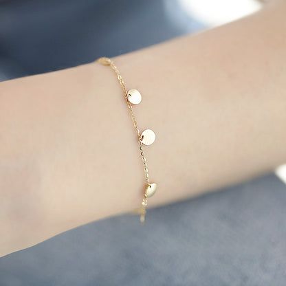 Een vergulde armband uit de set met witte schijven en hartvormige spacers.