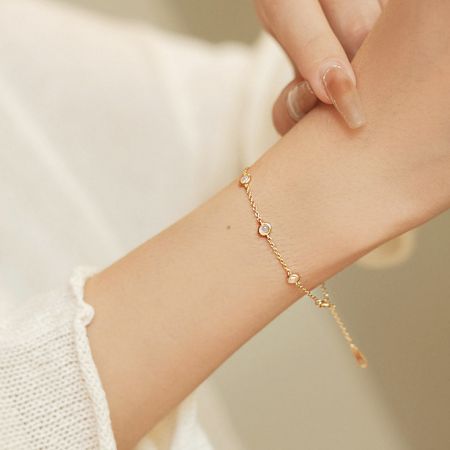 Modelo usando la pulsera de piedra ópalo chapada en oro de 18K, destacando su ajuste elegante en la muñeca.