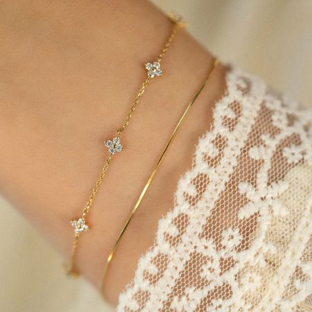 Modelo usando as pulseiras de flores de zircônia de ouro 18k em prata 925, demonstrando como podem ser sobrepostas.
