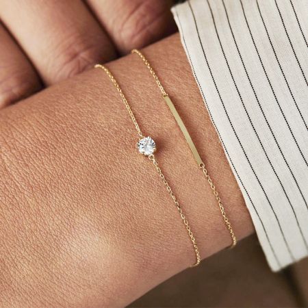 عارضة ترتدي سوار سلسلة رفيعة من الزركونيا المكعبة الذهبية، تظهر تصميمه الرقيق على المعصم.