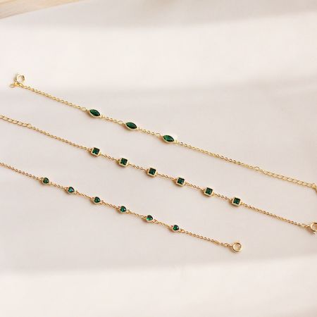 Detailed view of the three bracelet designs with unique green gemstone settings on a clean white background.