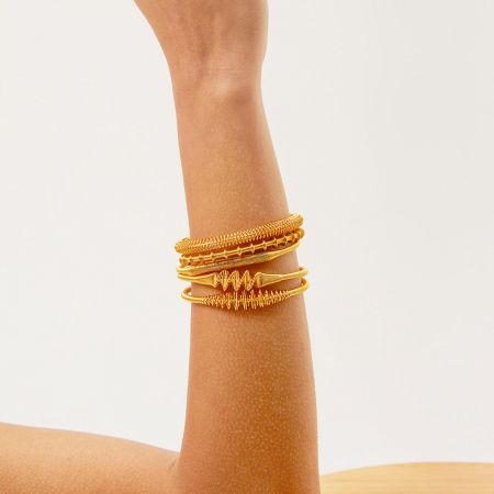Model's wrist adorned with a stack of Nordic vintage gold wire wrap bangles.