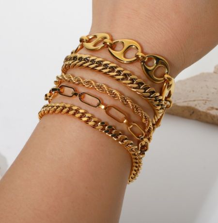 Bracelet plaqué or 18k OEM - Gros plan sur un poignet orné de plusieurs couches de bracelets élégants plaqués or 18k OEM, mettant en valeur leur finition polie et leur design.