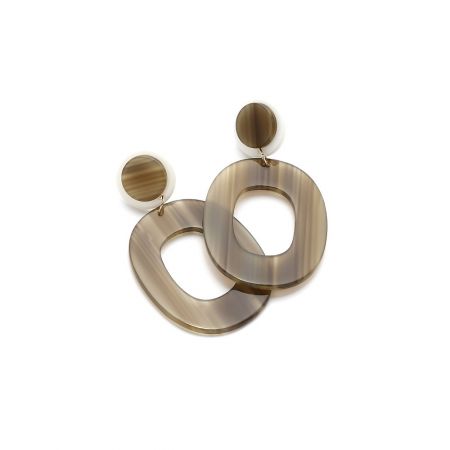 Détail du support en laiton plaqué or et finition en métal brossé sur les boucles d'oreilles pendantes ovales larges en résine.