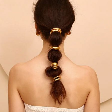 Un modelo que muestra la diadema en forma de labios dorados en un peinado de burbujas elegante.