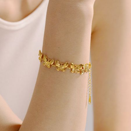 Vista detallada del charm de mariposa en la pulsera de acero inoxidable.