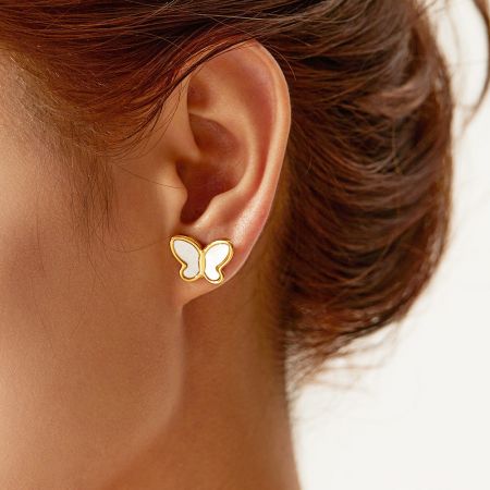 Vista en primer plano de una mujer que lleva pendientes de mariposa de oro con incrustaciones de nácar.