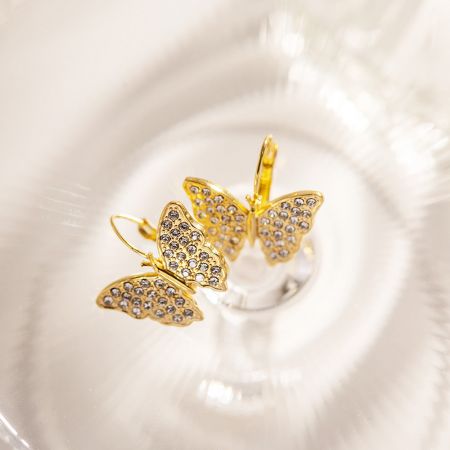 Eine detaillierte Nahaufnahme eines einzelnen goldenen Schmetterlingsohrrings, der die klaren Strasssteine zeigt.