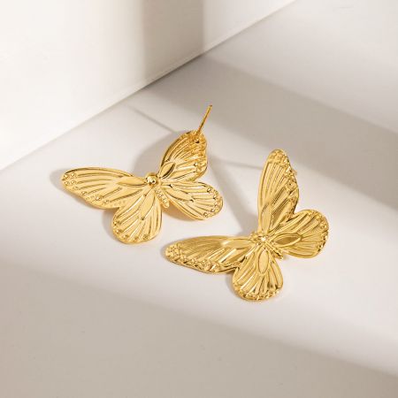 Un par de pendientes de mariposa dorada con intrincados detalles en las alas sobre un fondo blanco limpio.