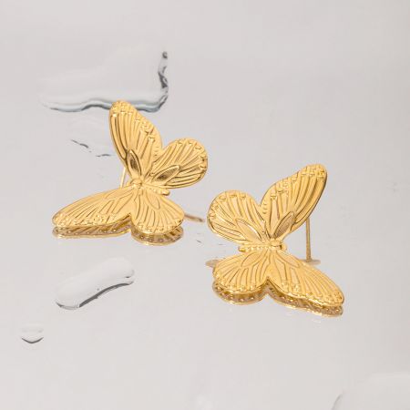 Otro ángulo de los pendientes de mariposa dorada, destacando su acabado brillante.