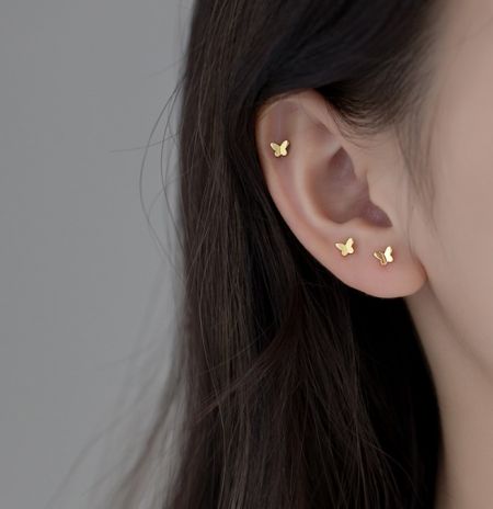 A model wearing the gold butterfly stud earrings to show scale and style.