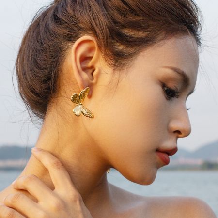 Pendientes de mariposa dorada grandes de acero inoxidable elegantes (5 pares) - Una modelo mostrando los elegantes pendientes de mariposa dorada grandes de acero inoxidable, destacando su apariencia al ser usados.