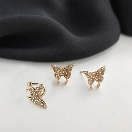 Vue détaillée des boucles d'oreilles en or en forme de papillon, mettant en valeur l'agencement complexe de pierres précieuses transparentes.