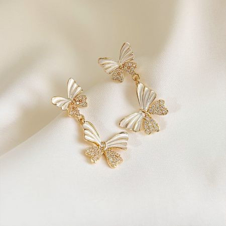 Close-up of the gold butterfly earrings highlighting the white wings and clear gemstones.