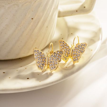 Das Paar goldener Schmetterling-Hakenohrringe, das zusammen präsentiert wird, um ihr elegantes Design zu zeigen.