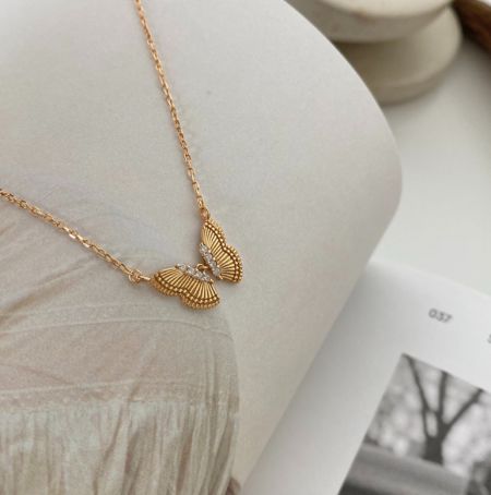 El collar de mariposa de plata esterlina exhibido en un maniquí blanco para mostrar cómo cuelga.
