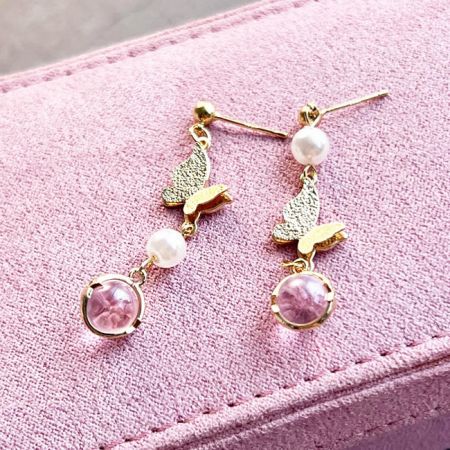 Full view of the gold butterfly and pearl earrings against a white background.