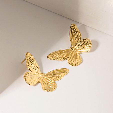 Toma detallada de los pendientes de mariposa dorada que muestran su diseño texturizado.