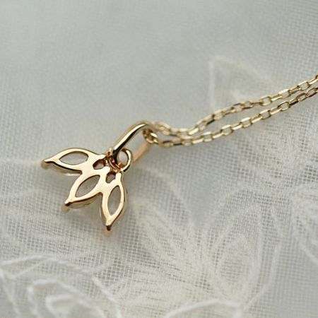 Encantador collar con colgante de mariposa dorada del conjunto, exhibido sobre una delicada superficie de encaje.